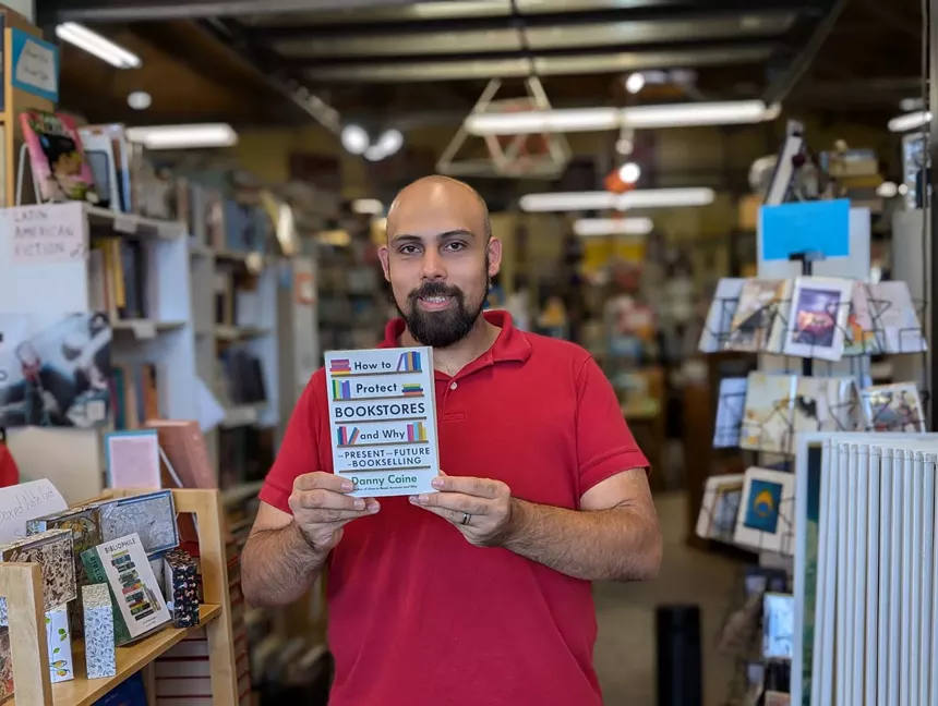 Matt Aragon-Shafi of West Side Books holding up a book