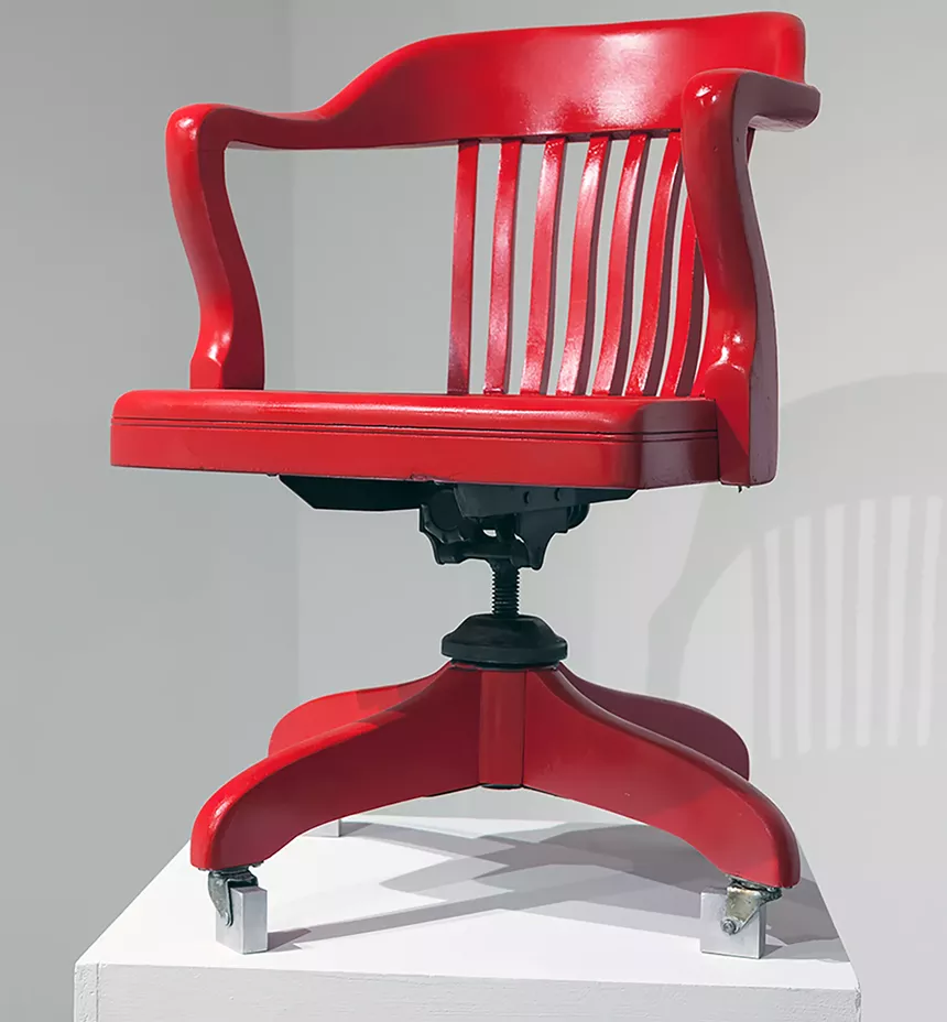 A red chair sits atop a white podium.