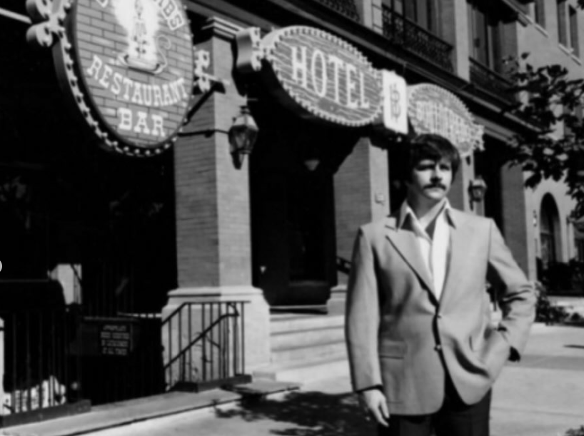 black and white photo of a man in front of a hotel