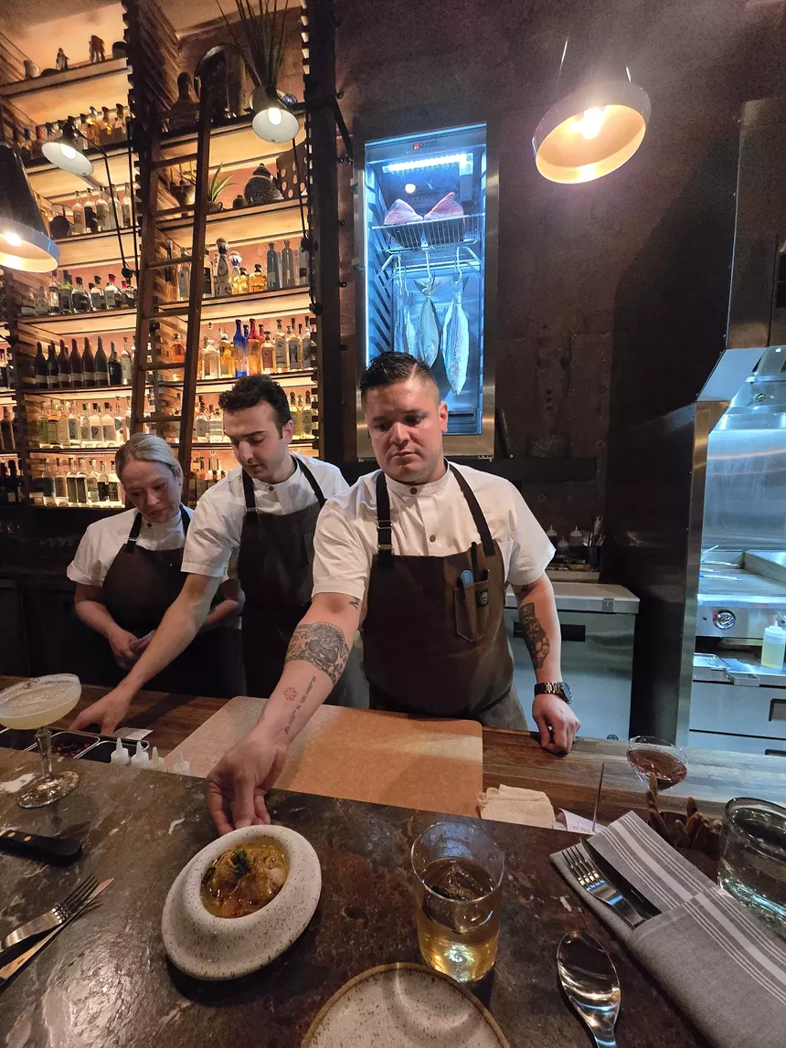 chefs in aprons serving food from behind a counter