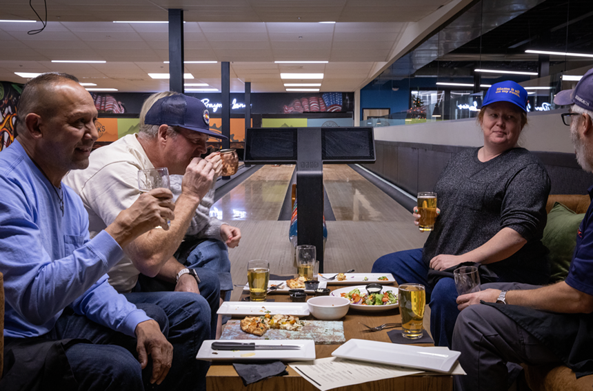 Patrons enjoying food in a bowling lane.