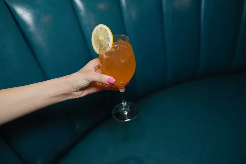 hand holding a cocktail with a lemon garnish