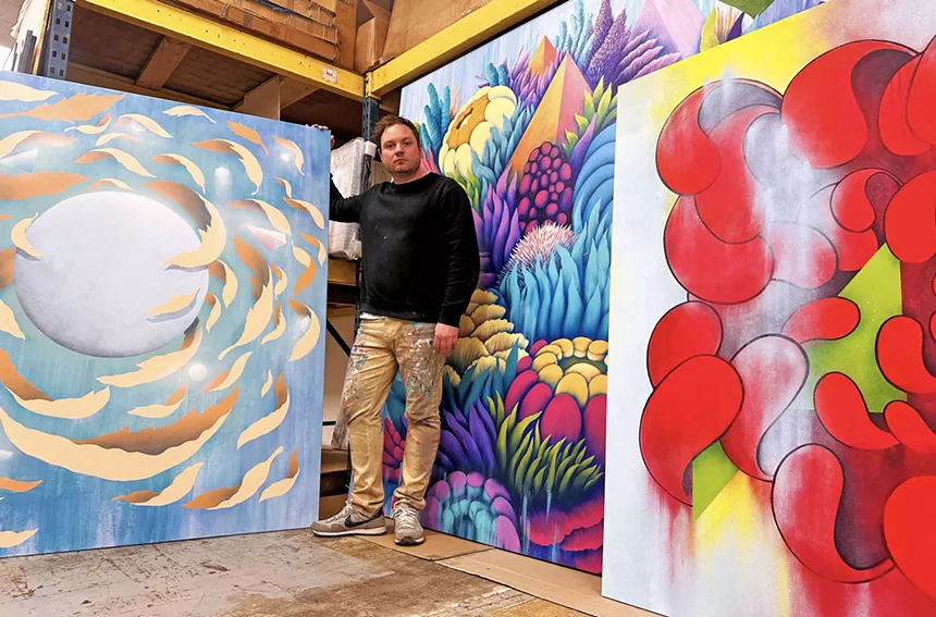 man standing around his paintings