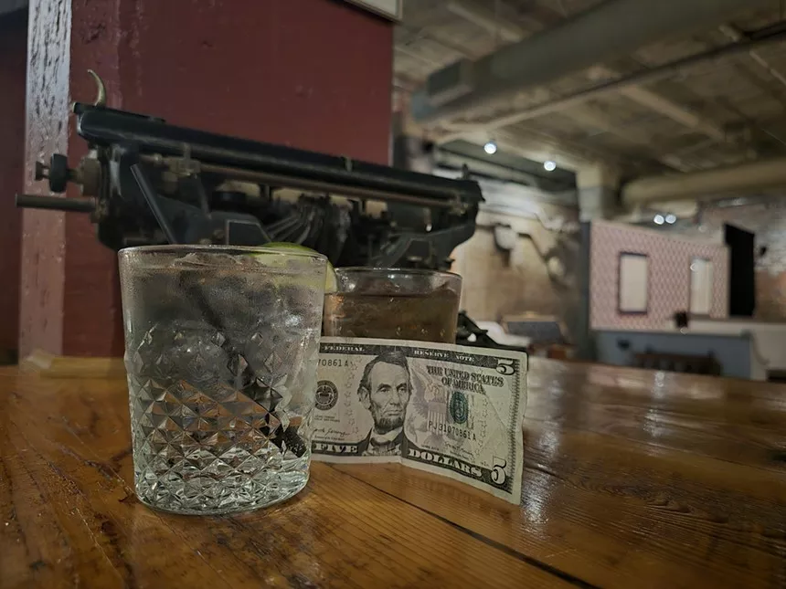 a five dollar bill next to a drink