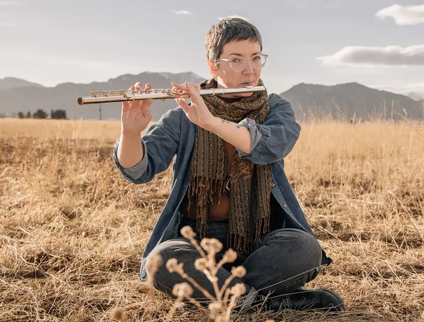 Sarah Christiansen playing the flute in a field.