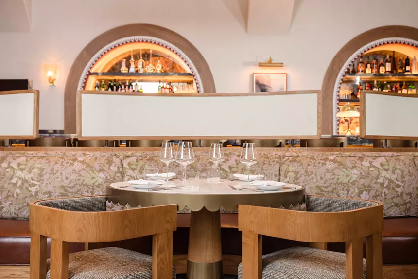 A table within Tavernetta Vail, featuring wood seating and earth tones
