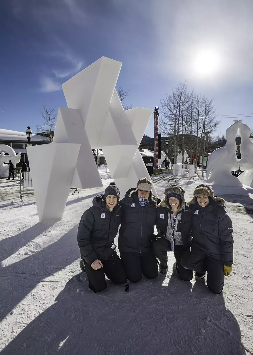 four people in parkas in front of ice sculptures