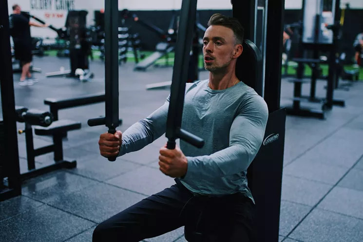 Man works out at gym with chest fly machine