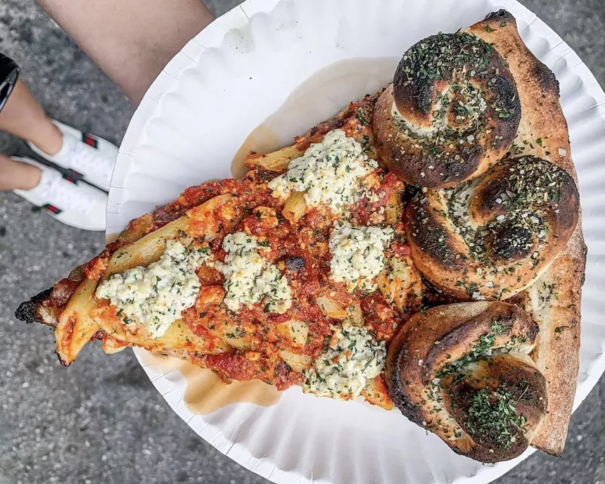 A thick slice from Mora Pizza topped with pasta and vegan cheese