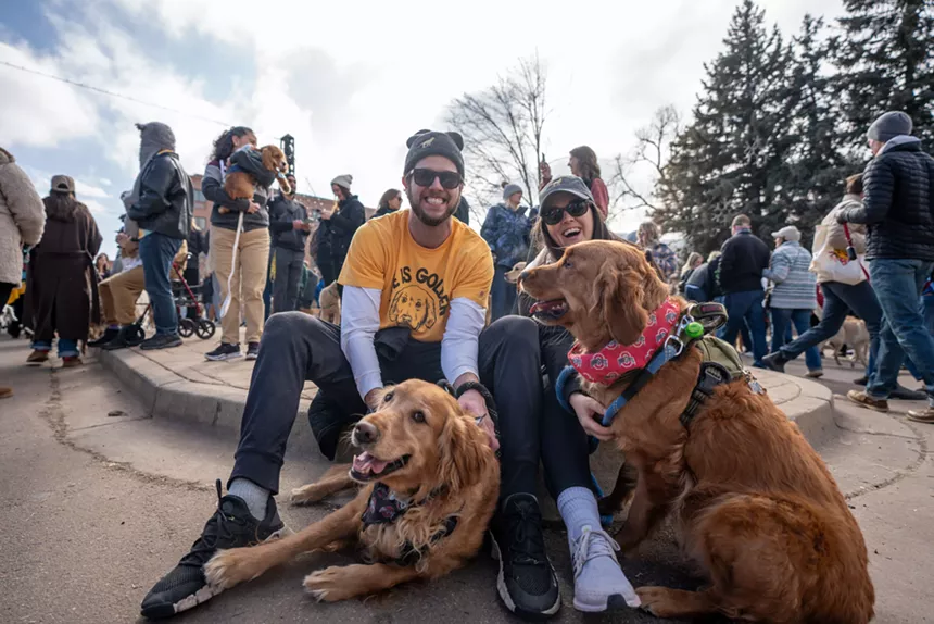 two people sit with their dogs