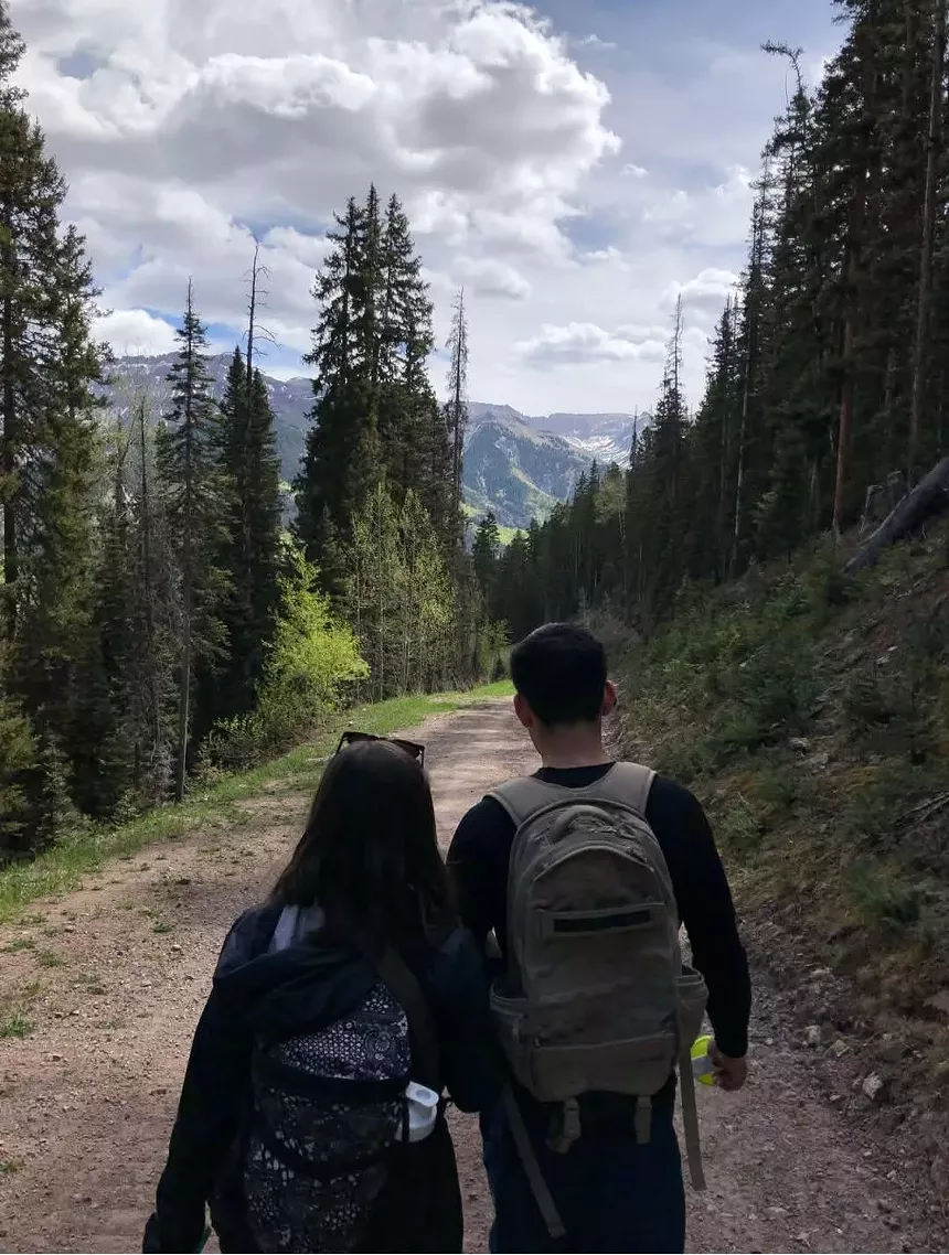 Two people walking together in the woods.