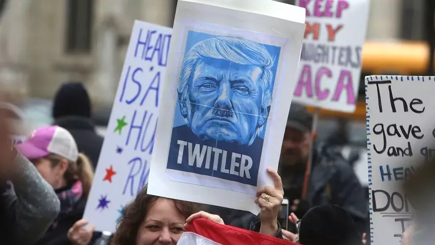 A protester holding a sign with a picture of Donald Trump with a Hitler mustache.
