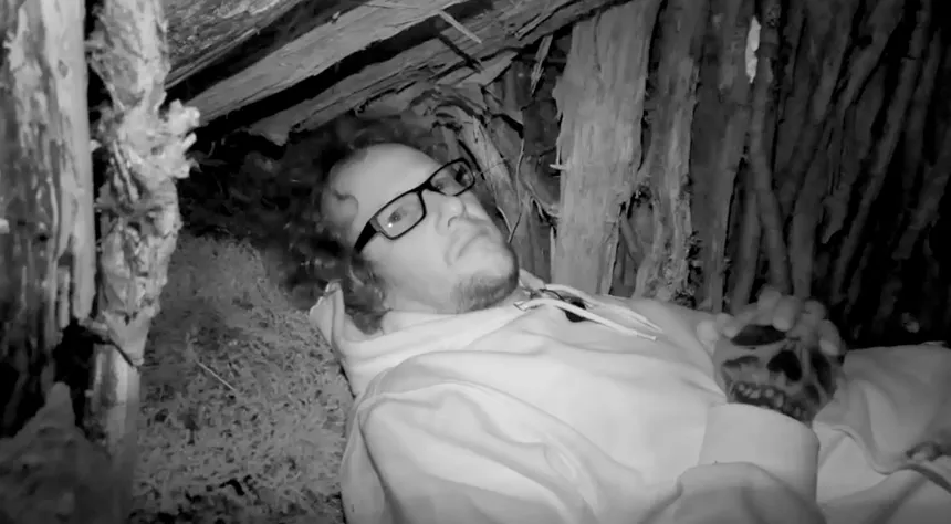 A black and white photo of Willis laid down in his shelter at night