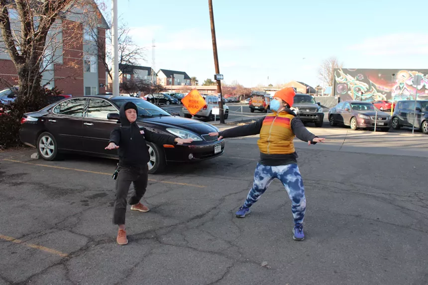 Two people are dancing in a parking lot.