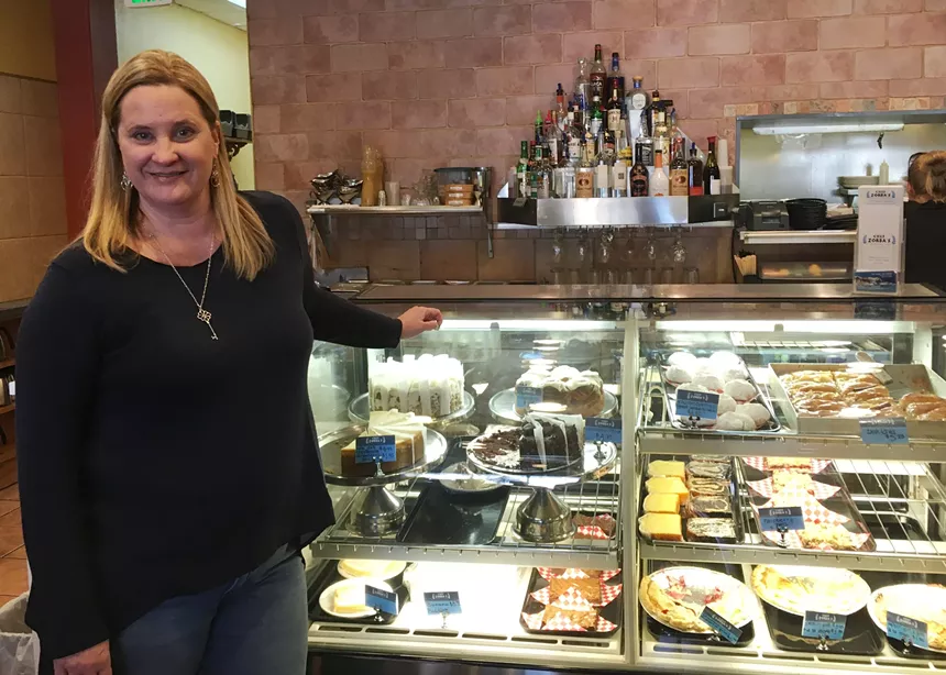 woman standing in front of a pastry case