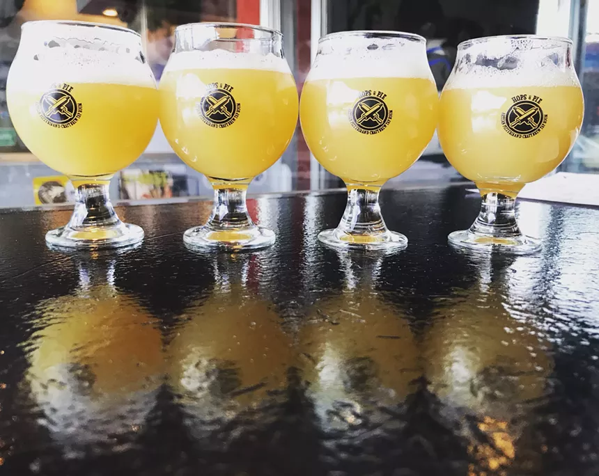 Photo of bright beers in glassware on a bar.