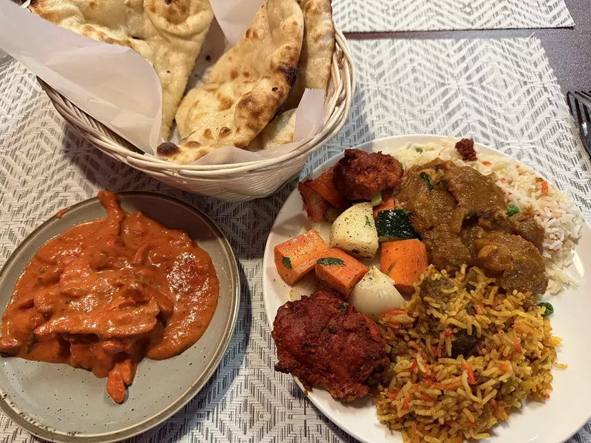 basket of naan and two plates of Indian food