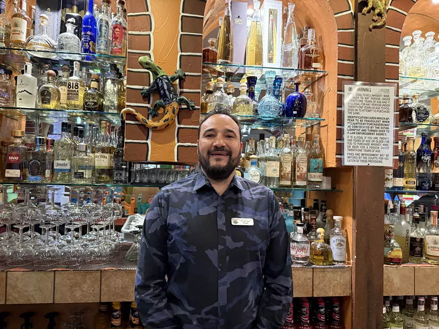 man posing in front of a stocked bar