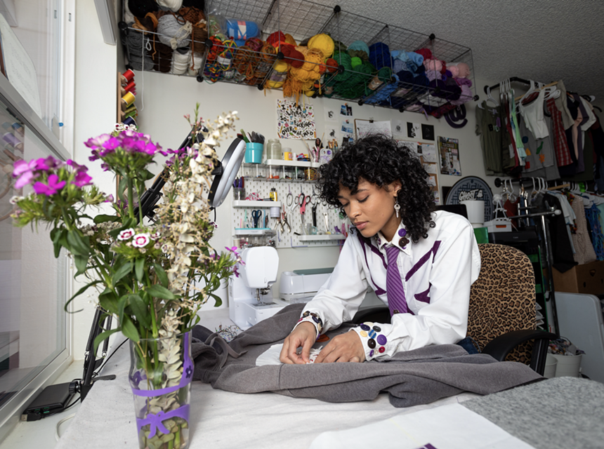 A woman works on a sweatshirt at a sewing machine