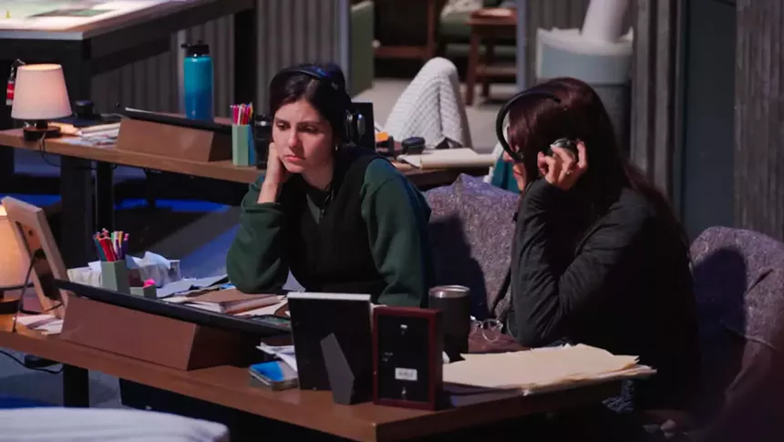 Nichols and Foster wearing headphones while sitting at a desk at headquarters