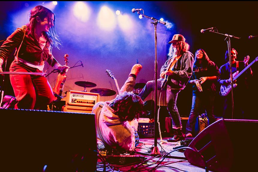 guitarist rolling on stage while band laughs