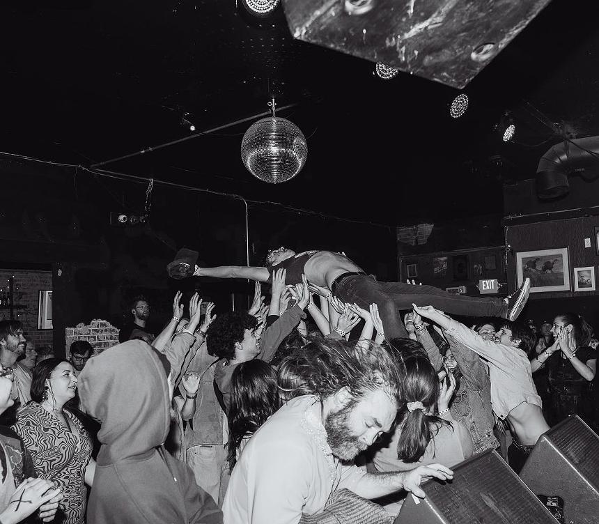 a person stage diving being held up by a crowd