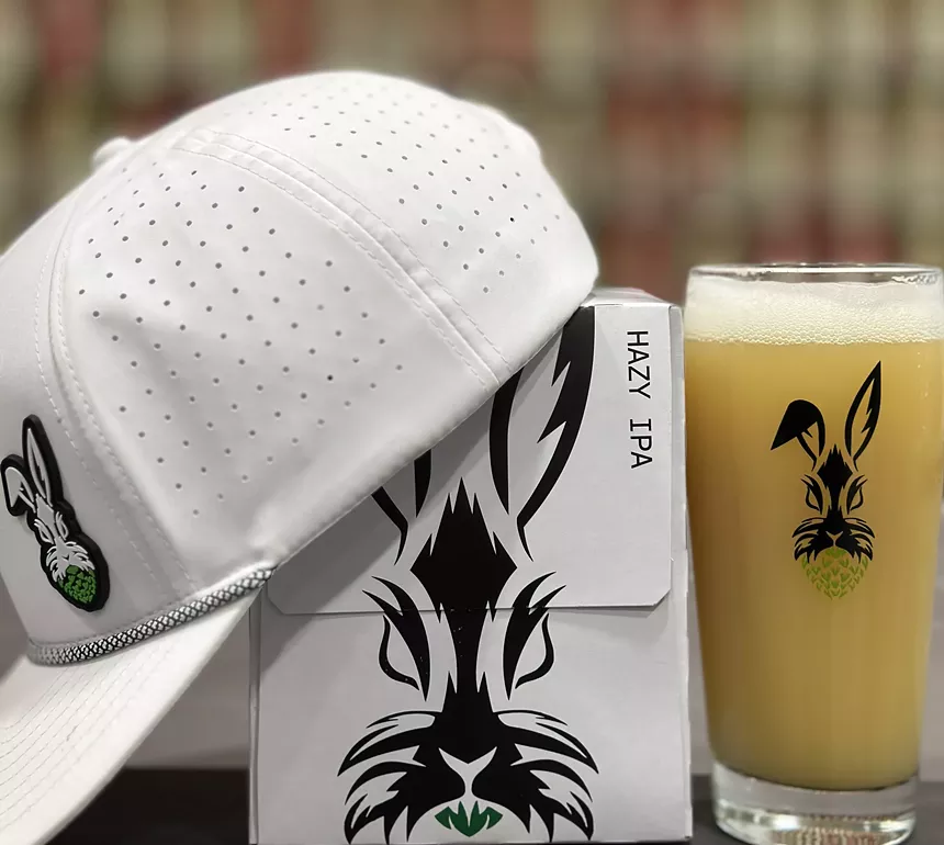 Beer hat and case with hazy IPA on background.