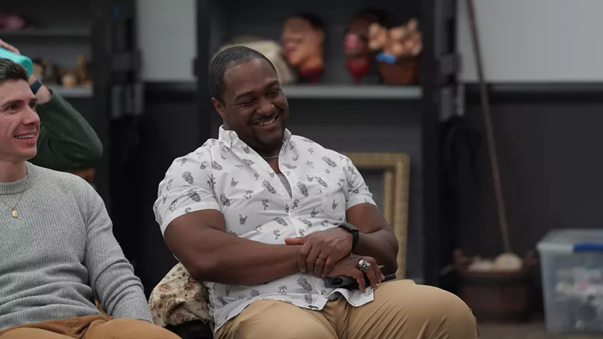 A man smiles with his arms crossed