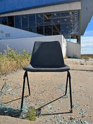 a chair in an abandoned location with broken glass on the ground
