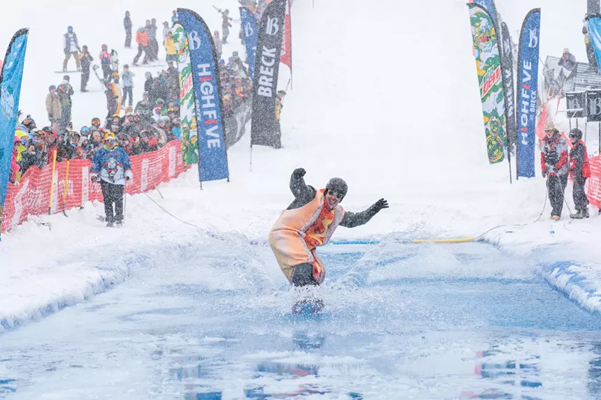 A man in a hot dog costume pond skimming at Breckenridge Ski Resort