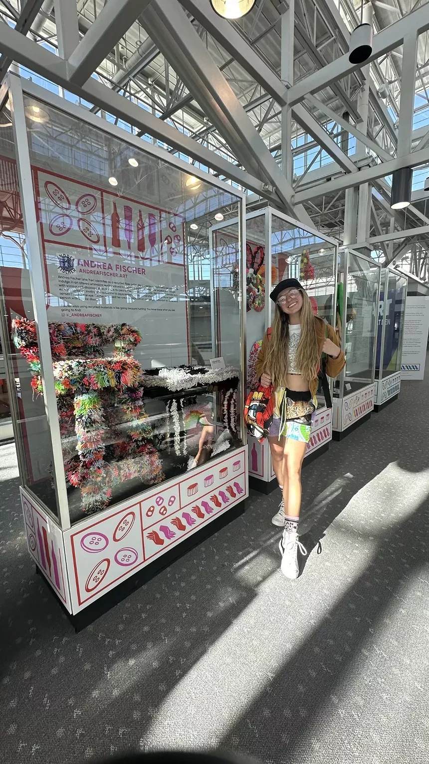 A woman stands next to an art display in the airport