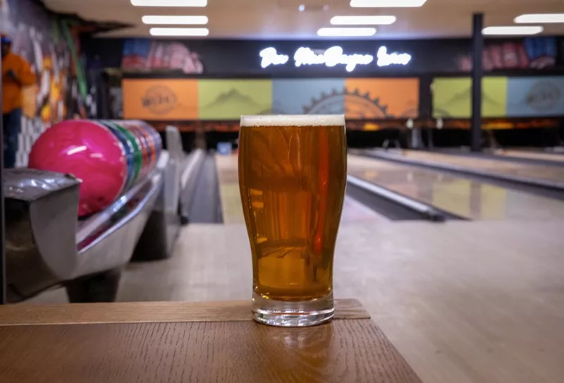 A pint of beer backdropped by bowling lanes at the Werks