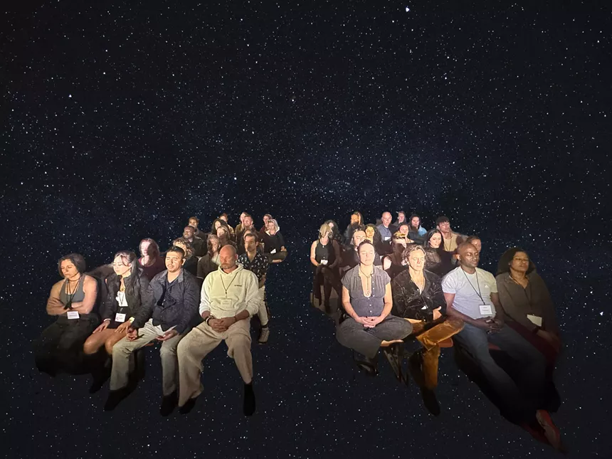 people sitting in chairs over a backdrop of space
