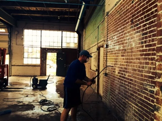 A man power-washes a wall.