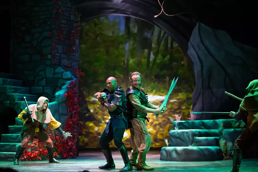 Two actors stand back-to-back with swords onstage.