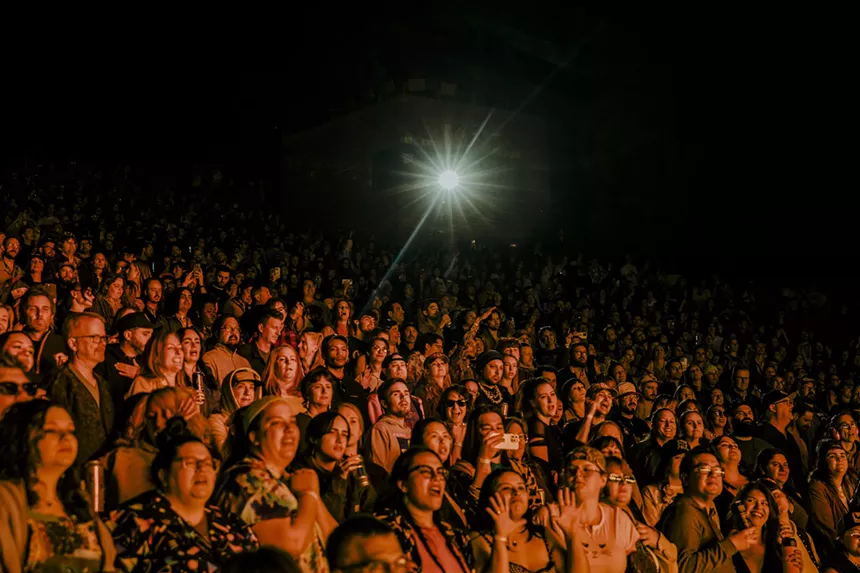 A photo of fans at Red Rocks with a spotlight shining onto the crowd.