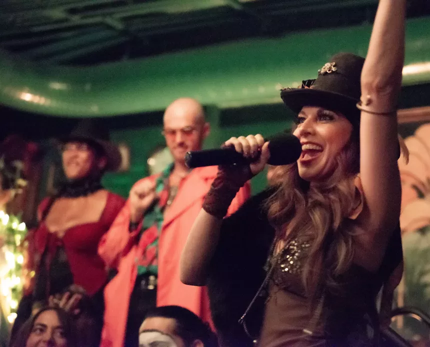 A woman at a microphone with her arm raised