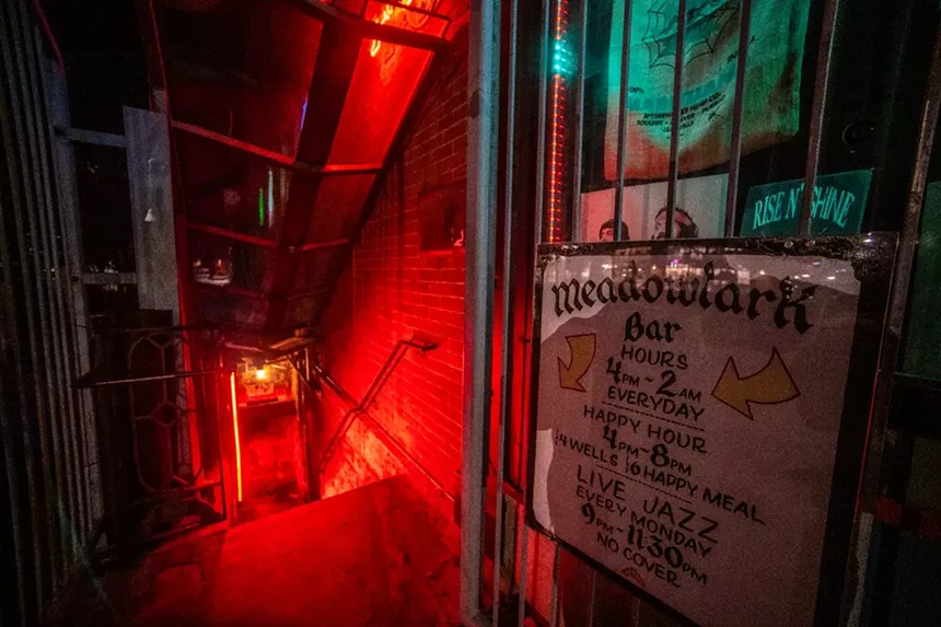 sign at the top of a stairwell reading "Meadowlark Bar"