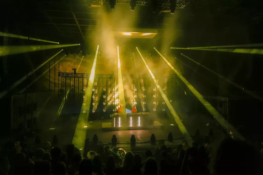 A photo of Polo & Pan performing at Red Rocks with stage lights shining behind them.