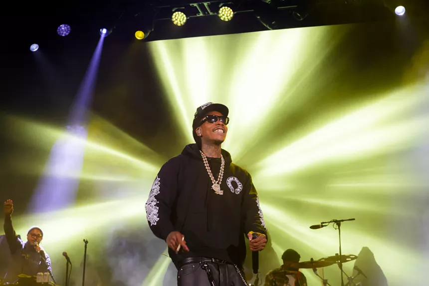 A photo of Wiz Khalifa on stage at Red Rocks smiling at the crowd.