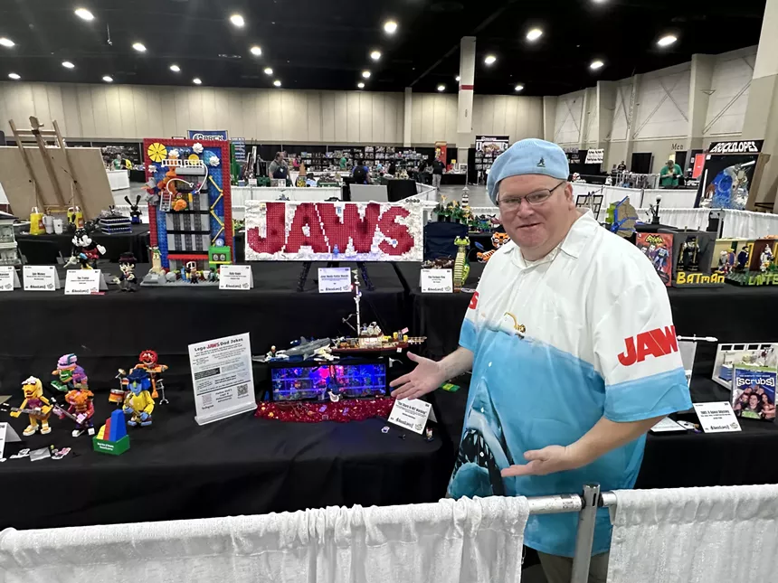 A man stands next to a table of LEGO sets