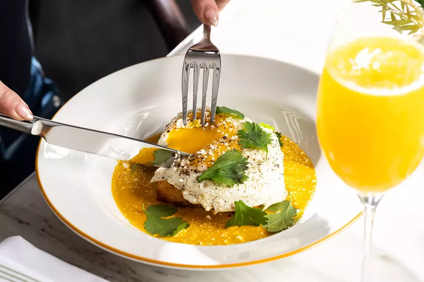 A diner cutting into an egg entree from Chez Maggy