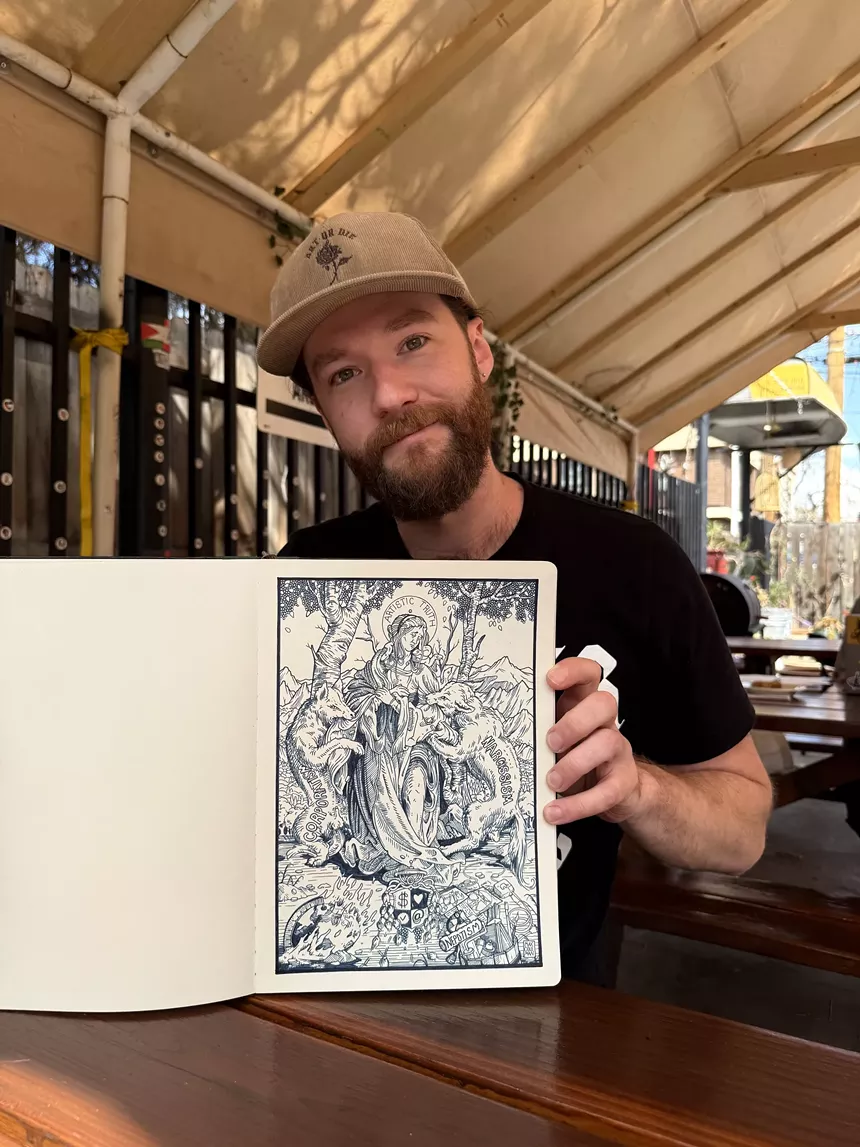 A man holds a sketchbook with a line drawing