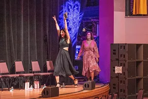 Women walk on stage.