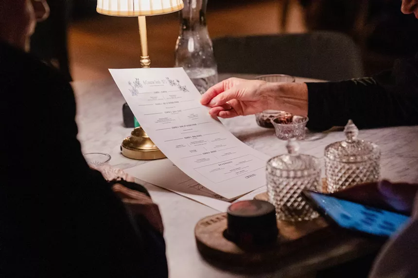 A person holding a prix fixe menu from Cirrus Social Club