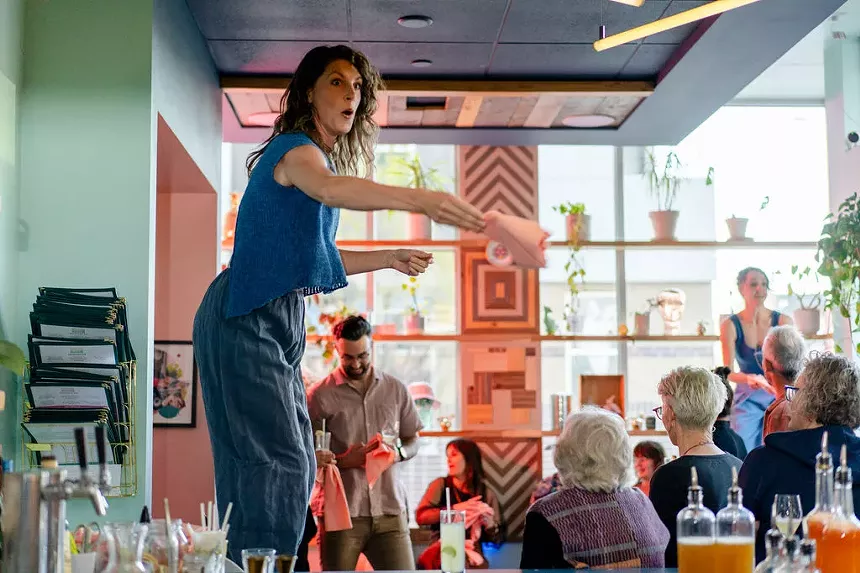 Women stand on a table in a restaurant to address the crowd.