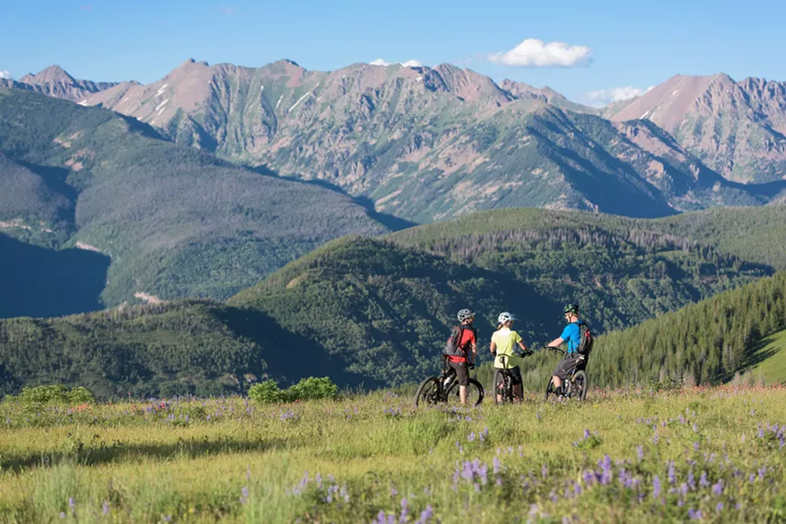Three mountain bikers backdropped by Vail Valley scenery