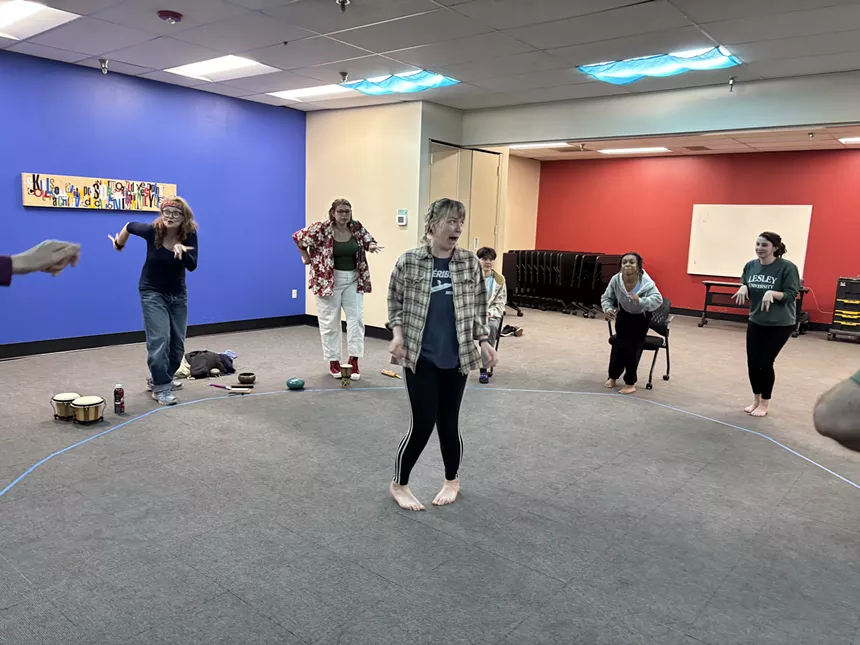 A group of disabled artists form a circle around a woman in the center.