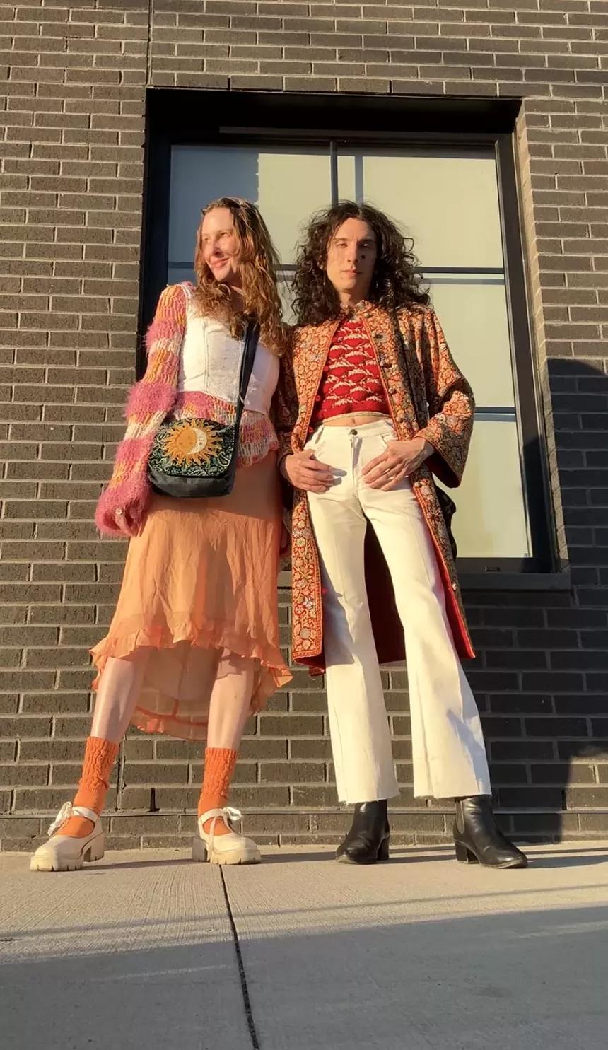 Two people stand outside in bright outfits