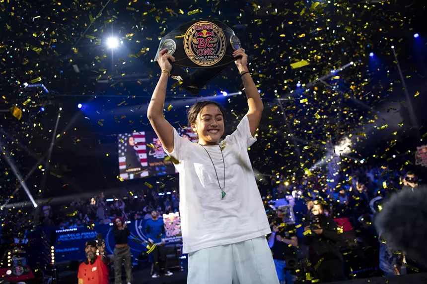 A woman raises her belt above her head.